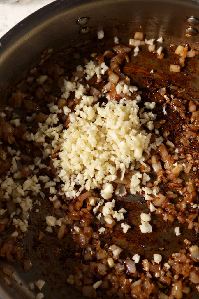 Minced garlic in a skillet with cooked shallots