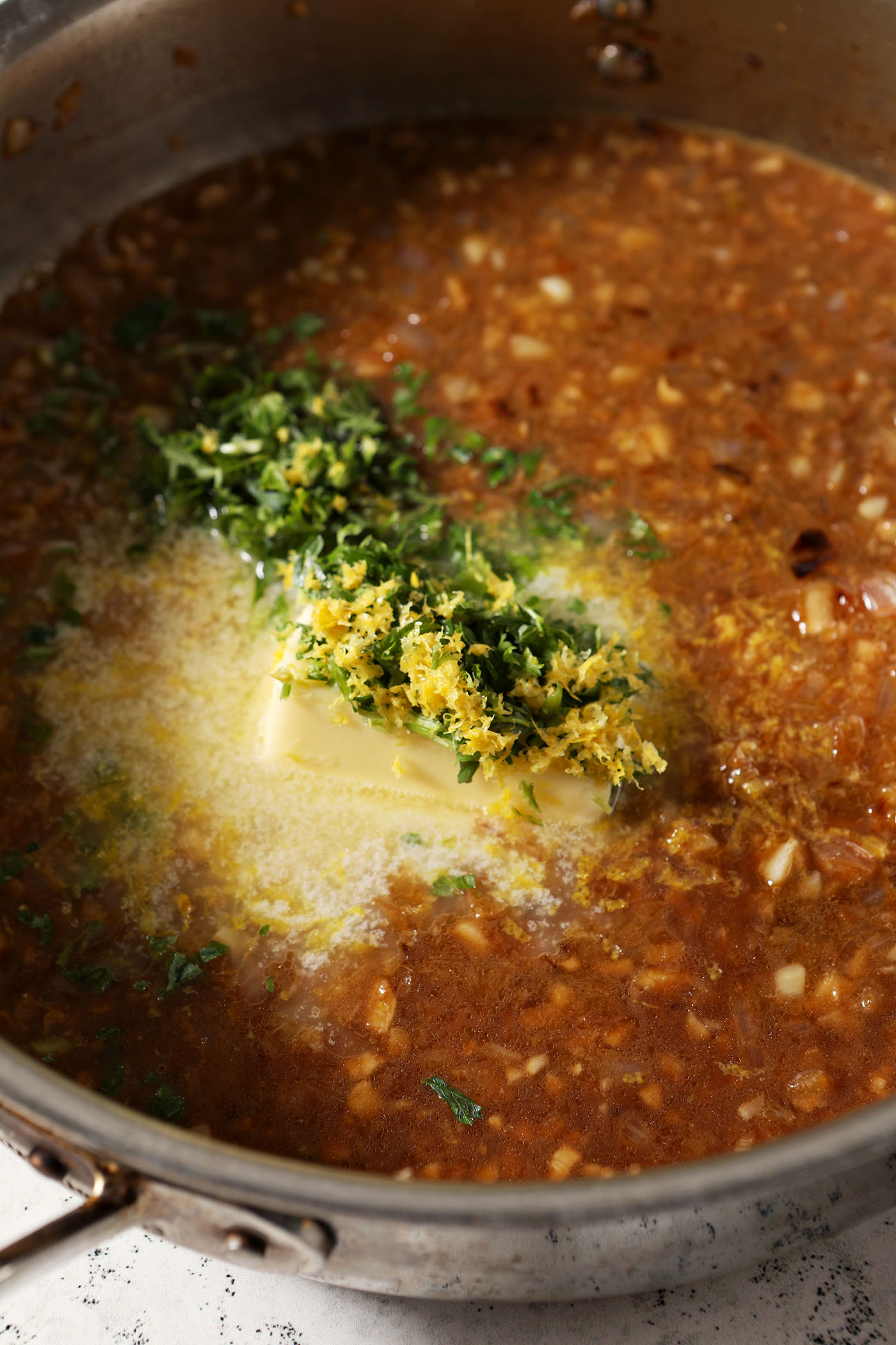 Melting butter with lemon zest and parsley in a skillet with a brown sauce