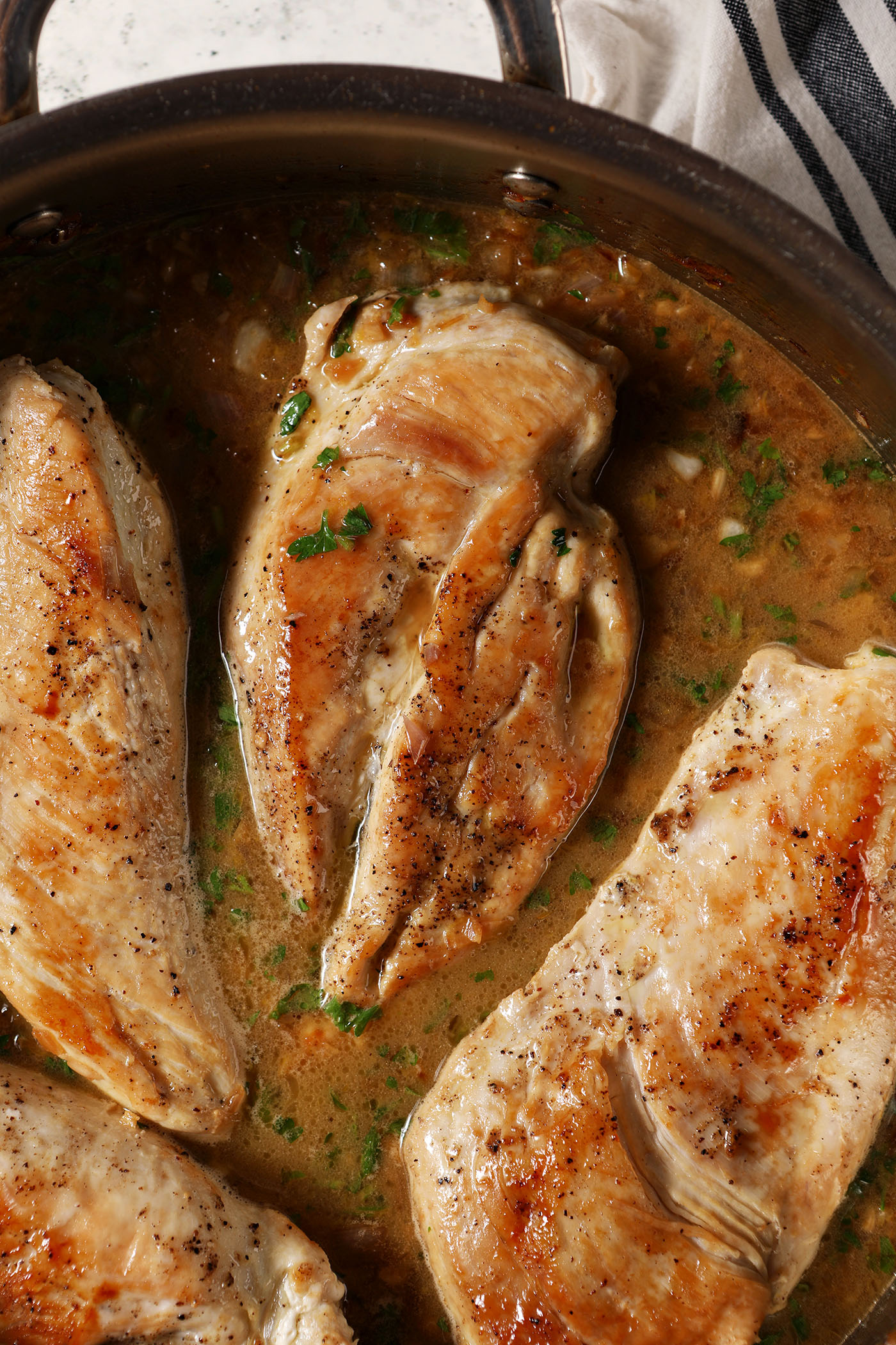 Chicken breasts in a skillet with a lemony sauce