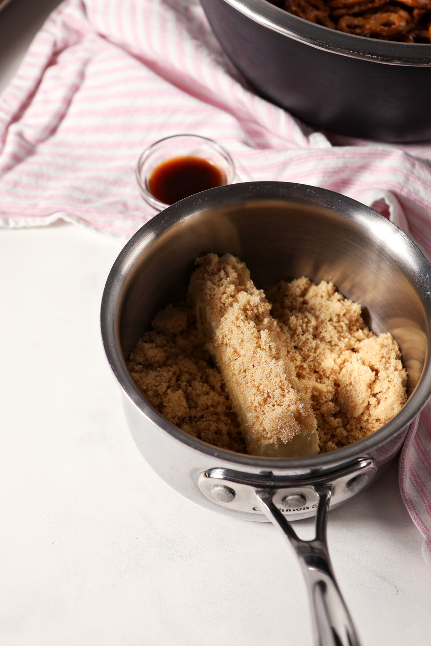 Ingredients to make butter toffee in a small saucepan on a white stone surface
