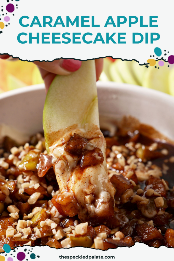 an Apple being pulled out of Caramel Apple Cheesecake Dip in a white serving dish with different dippers around it.