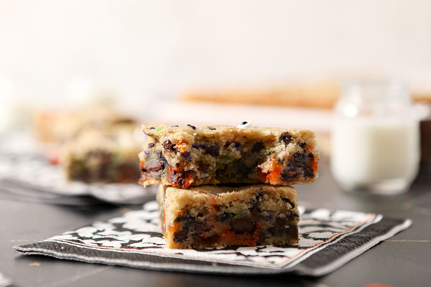 Two Halloween cookie bars stacked on top of each other on top of a black and white bat paper napkin