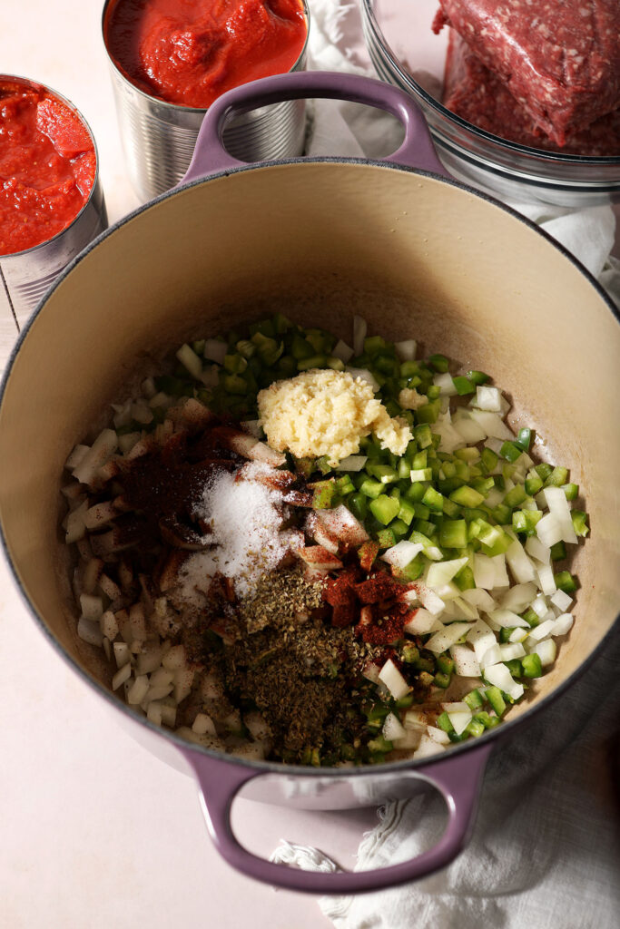 Vegetables in a purple Dutch oven before cooking down with spices
