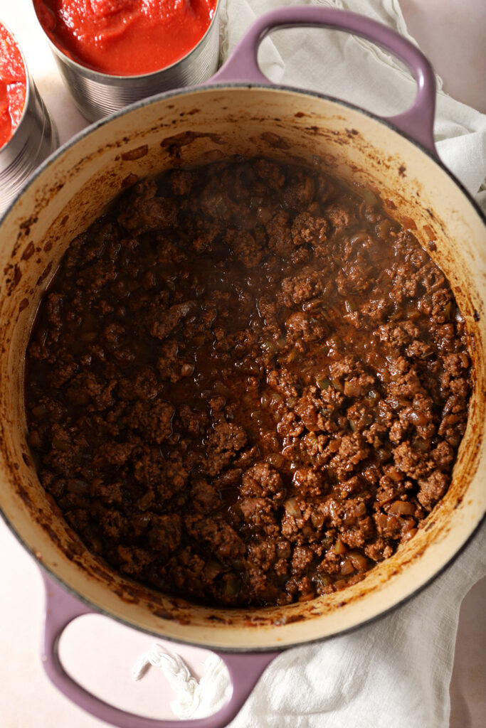 Ground bison, cooked vegetables, and beef stock simmer in a pot