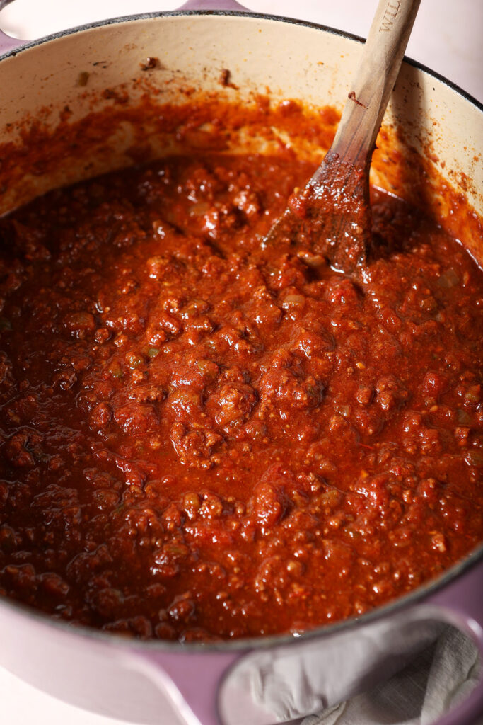 Spicy Bison Chili in a Dutch oven with a wooden spoon